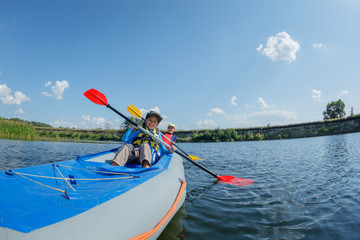 Happy boy kayaking on the river on a sunny day during summer vacation