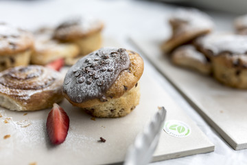 A delicious, freshly baked chocolate covered chocolate chip muffin frosted or spinkled with icing sugar on a business breakfast buffet in the UK