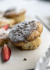 A delicious, freshly baked chocolate covered chocolate chip muffin frosted or spinkled with icing sugar on a business breakfast buffet in the UK