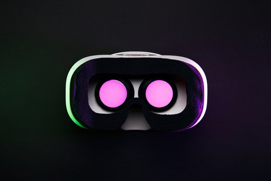 Picture of virtual reality glasses with burning pink light on black background