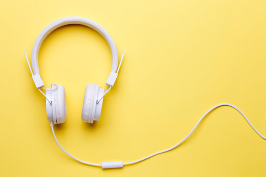 Image of white headphones for music on yellow background