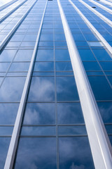 Fototapeta na wymiar Abstract background of facade of modern glass building with white clouds reflected in it.