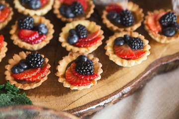 Small tartalettes with berries on wooden cutting board