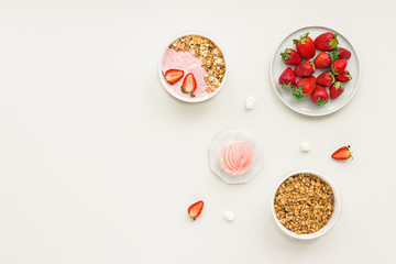 Healthy breakfast with yogurt, muesli, fruits, strawberry on grey background, flat lay, top view