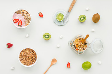 Fototapeta na wymiar Healthy breakfast with yogurt, muesli, fruits, strawberry on grey background, flat lay, top view