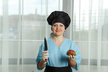 the woman the cook holds in one hand a fruit of mango and in other hand a knife. horizontal image.