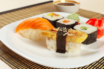 Assorted sushi and rolls and soy sauce on a bamboo mat close up.