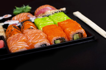 Big sushi set in black plate on black background/ top view close up macro shoot