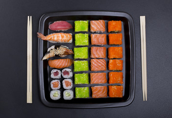 Big sushi set in black plate on black background/ top view close up macro shoot