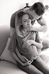 Young pregnant woman with husband at home, black and white effect