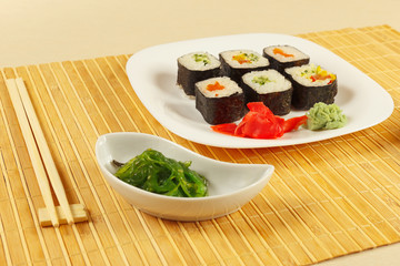Sushi set, hiyashi wakame salad with ginger and wasabi on a bamboo mat close up.