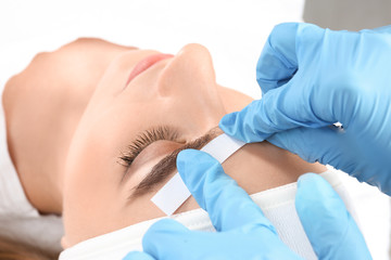 Obraz na płótnie Canvas Young woman having professional eyebrow correction procedure in beauty salon