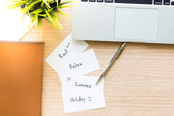 Workplace top view of  Wooden desktop with laptop, pen, notebook and paper note for holiday summer concept © flyalone