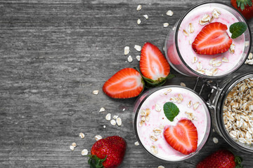 two glasses of healthy strawberry yogurt with fresh berries, oats and mint on rustic wooden table