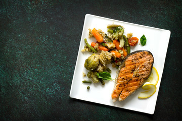 Grilled salmon steak, couscous and vegetables on stone or concrete table. Healthy proper nutrition. Copy space, top view flat lay background.