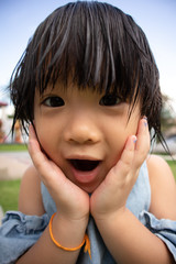 Asian little playful girl rest her chin on hands and open mouth