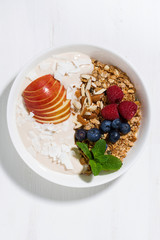oat granola with apples and berries on white background, vertical top view