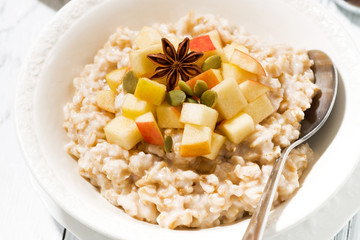 plate of oatmeal with apples and spices, closeup top view