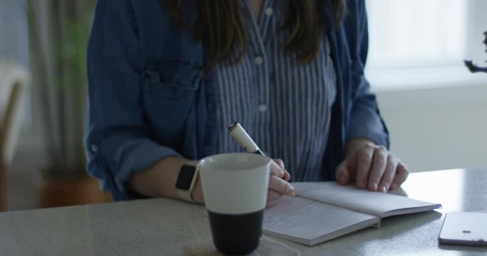 Young woman writing notes - writers block - close up on pen and notebook