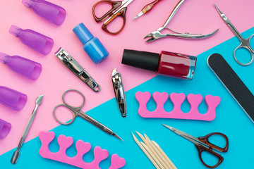 Manicure or pedicure tools scattered on a pink and blue background.