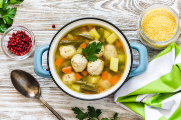 Pork ricotta meatball soup in a pot on white wooden background. Top view, space for text.