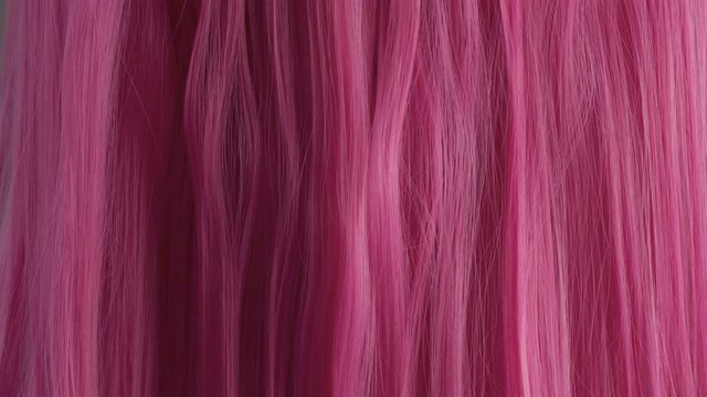 Closeup of pink hair creative colored texture Woman's hand with pin manicure slide touching pink hair