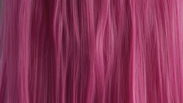 Closeup of pink hair creative colored texture Woman's hand with pin manicure slide touching pink hair