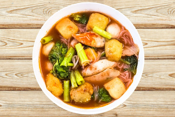 Thai food.Pink seafood flat noodles.Spicy lemongrass flavored soup with pork, chicken on wood background.Close up.Clipping path