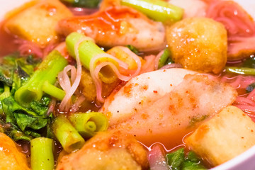 Thai food.Pink seafood flat noodles.Spicy lemongrass flavored soup with pork, chicken on background.Close up