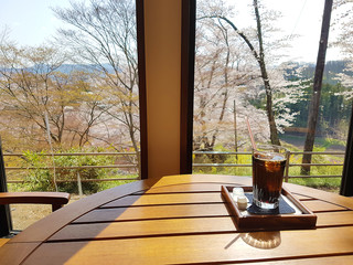 Morning coffee on the terrace in cafe. Cup of ice americano on the table in sun light with cherry...