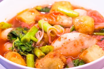 Thai food.Pink seafood flat noodles.Spicy lemongrass flavored soup with pork, chicken on background.Close up