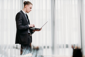 Fototapeta premium business man reading documents on laptop in his office. stylish young handsome executive at work