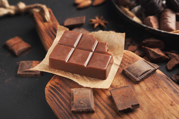 Bar of milk chocolate on wooden cutting board