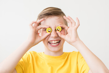 Cheerful laughing teen boy with yellow smiley faces instead of eyes