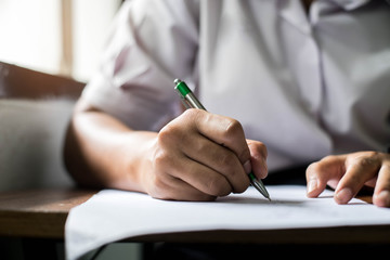 Close up Students writing and reading exam answer sheets exercises in classroom of school with stress.