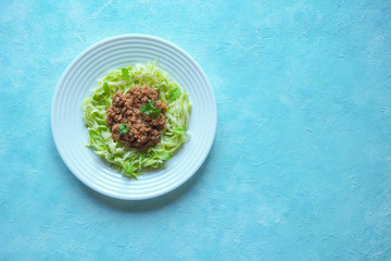Plate of Zucchini spaghetti with beef bolognese on a blue background.