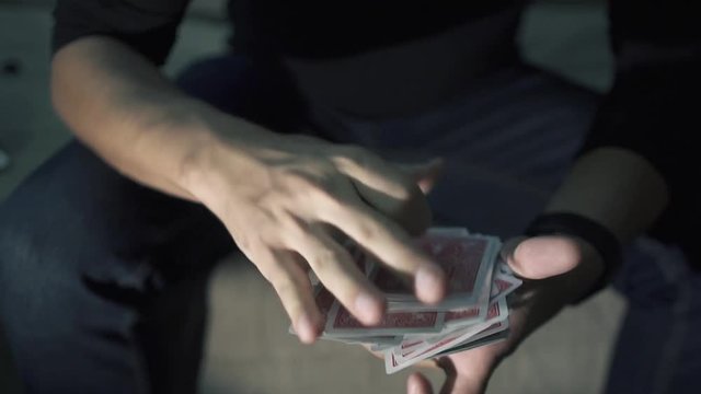 The cards fly from one hand to the other. manipulation with a deck of cards. shuffle cards. The magician works with a deck of cards. Slow motion