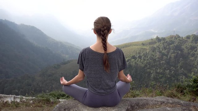 Yoga woman sits in meditation pose padmasana on mountain cliff in Sapa, Vietnam