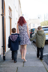 Mother walking to school with children down a British Street