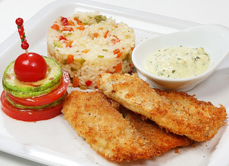 Fillet of sea bass with golden crust, served with rice, zucchini and cherry tomato