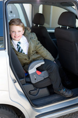 Schoolboy sat in car seat, ready to go back to school