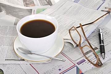 hot cup of black coffee on the table with newspaper