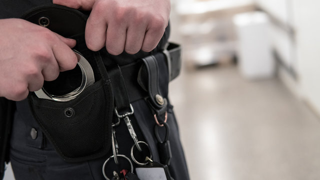 Police offiser or security staff takes up handcuffs for arrest of criminal.