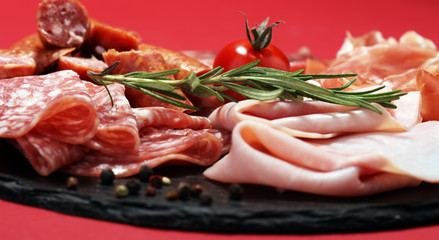 Food tray with delicious salami, ham,  fresh sausages and herbs. Meat platter with selection