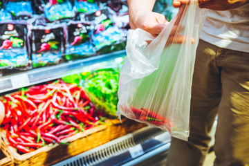 man choosing hot red pepper in supermarket. grocery shopping