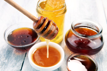 Pouring aromatic honey into jar, closeup