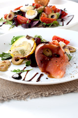 salmon salad greens olives white plate sauce