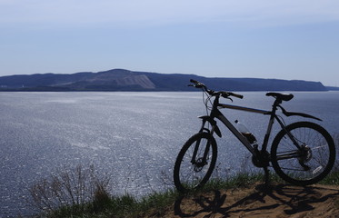 Fototapeta premium Silhouette of a sport bike against the background of a big river. There are mountains in the distance. Blue sky .