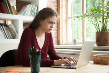 Puzzled unhappy female worker getting suspicious about online news and reports, thinking about company problems. Frustrated student concerned about strange email notification received on laptop
