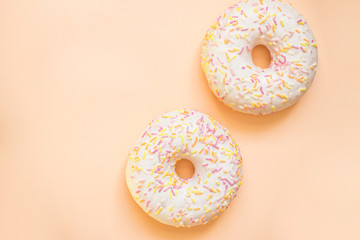 Donut with white icing colored topping, isolated on yellow background.Tasty classic two glazed donuts isolated.Delicious colorful donuts